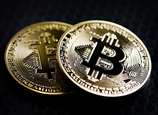 Dwie złote monety z symbolem Bitcoina na ciemnym tle